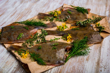 Raw fish flounder in fresh herbs on paper