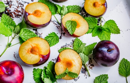 Composition with fresh plums and fresh mint on a white backgroundの写真素材