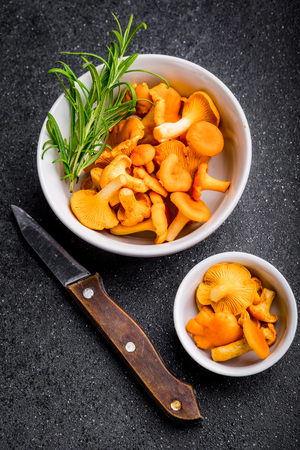 Raw wild chanterelle mushrooms in a bowls on a black backgroundの写真素材