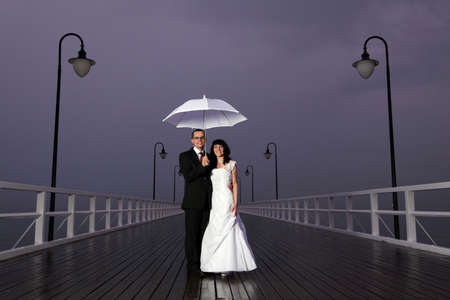 bride and groom, pier cloudy dusk sky.の写真素材