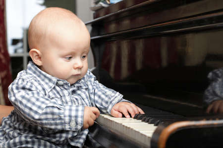 beautiful little baby boy plays pianoの写真素材