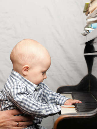 beautiful little baby boy learning plays pianoの写真素材