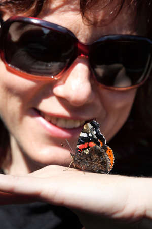 Woman playing with a butterfly outdoor in eyeglassesの写真素材