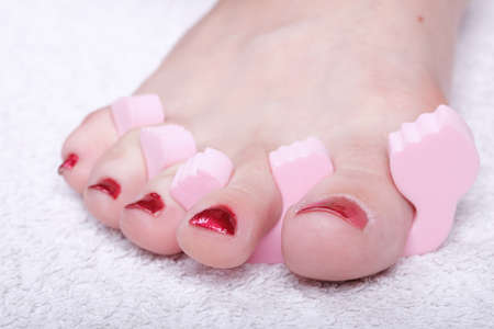 Close-up of female feet with red polished nails carefree, chiropodyの写真素材