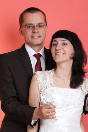 Happy smiling bride and groom on red backgroundの写真素材