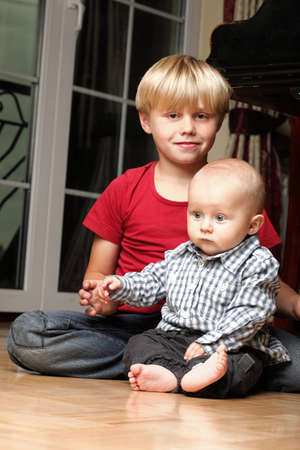 Blond boy with his newborn baby brother indoorの写真素材