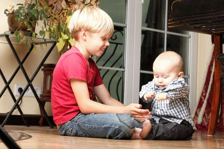 Blond boy with his newborn baby brother indoorの写真素材