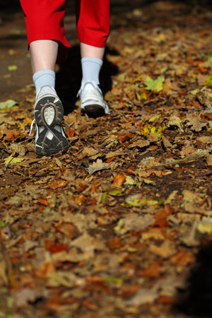 Woman walking cross country and trail in autumn forest