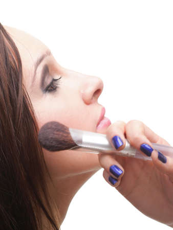beautiful young brunette woman applying powder with a brush isolated on whiteの写真素材