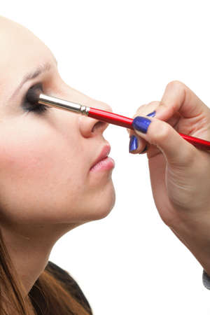 Woman applying eyeshadow using professional makeup brush isolated on whiteの写真素材