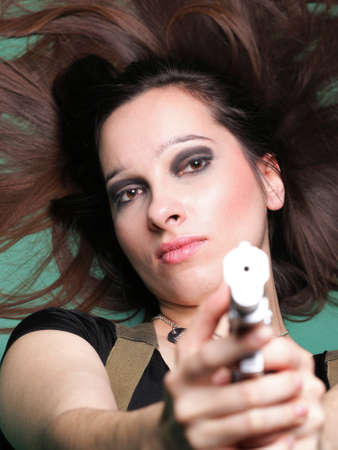 Sexy young woman in red with a gun, on green backgroundの写真素材