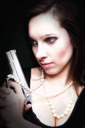 Sexy young woman with a gun, pearl on green backgroundの写真素材
