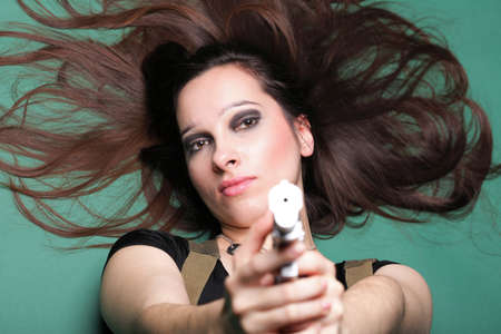 Sexy young woman in red with a gun, on green backgroundの写真素材