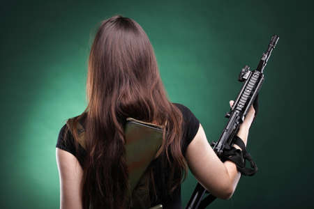 Beautiful woman with rifle plastic Military Army girl Holding Gun green backgroundの写真素材