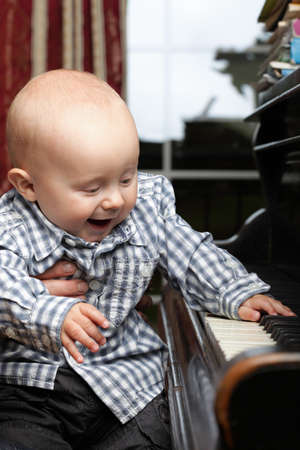 beautiful little baby boy learning plays pianoの写真素材