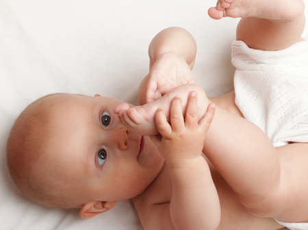 baby boy in diaper on white, blue eyeの写真素材