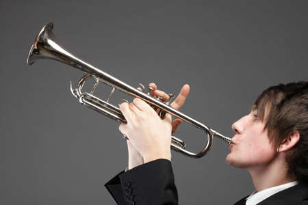 Portrait of a young jazz man playing his Trumpet grey backgroundの写真素材