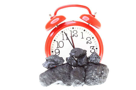 Pieces of coal and red clock isolated on white backgroundの写真素材