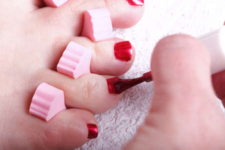 Close-up of female feet with red polished nails carefree, chiropodyの写真素材