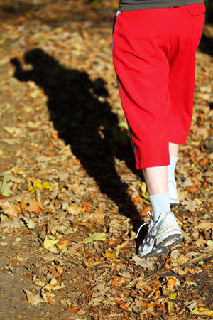 Woman walking cross country and trail in autumn forestの写真素材