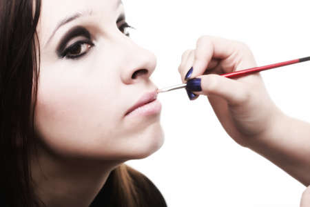 beautiful young brunette woman applying lips make-up zone isolated backgroundの写真素材