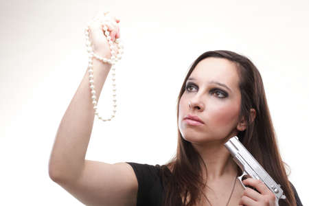 Sexy young woman with a gun and pearl isolated on whiteの写真素材