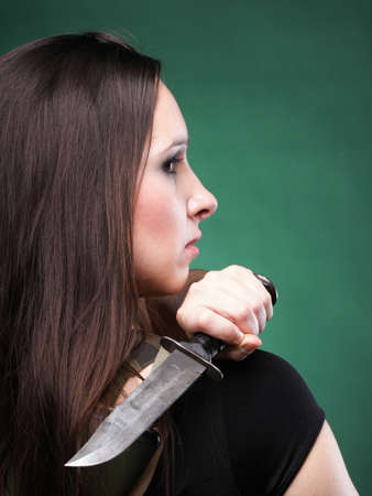 Sexy young woman in red with a gun, knife on green backgroundの写真素材