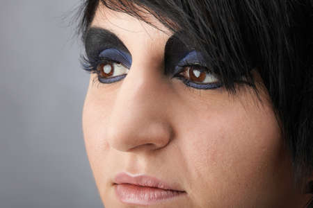 Beautiful woman face in studio. Blue and black. Grey background. Portrait of woman. Professional make up and hair style.の写真素材
