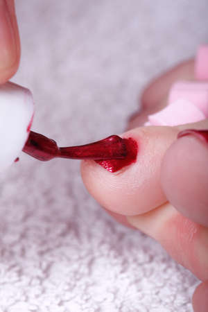 Close-up of female feet with red polished nails carefree, chiropodyの写真素材