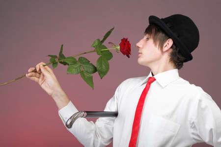 Young men with the red rose on colour background. Love and reflection.の写真素材