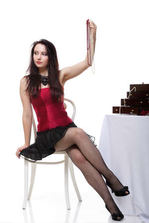 Woman admire jewellery hand - girl in red corset chair white isolated showgirlの写真素材