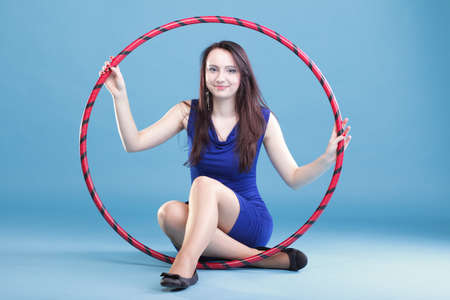 Beautiful woman in a sport wear. Dance hoop gym exercises blue backgroundの写真素材