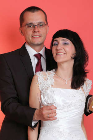 Happy smiling bride and groom on red backgroundの写真素材