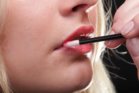 Beautiful woman putting on makeup red lipstickの写真素材