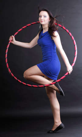 Beautiful woman in a sport wear. Dance hoop gym exercises black backgroundの写真素材