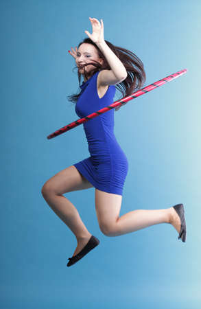 Beautiful woman in a sport wear. Dance hoop gym exercises blue backgroundの写真素材