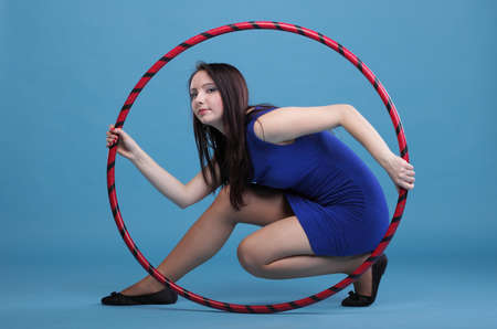 Beautiful woman in a sport wear. Dance hoop gym exercises blue backgroundの写真素材