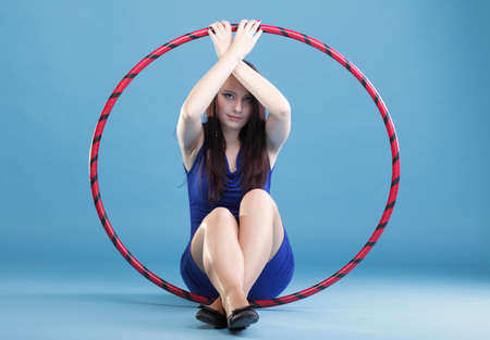 Beautiful woman in a sport wear. Dance hoop gym exercises blue backgroundの写真素材