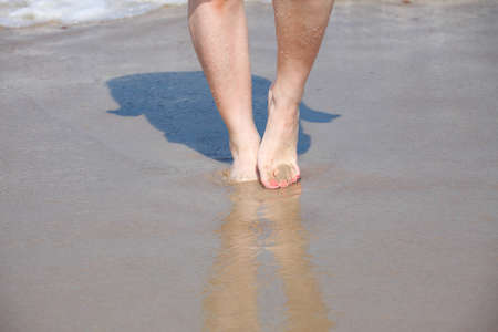 nice legs in water, nice pedicure red nail on sandy beachの写真素材
