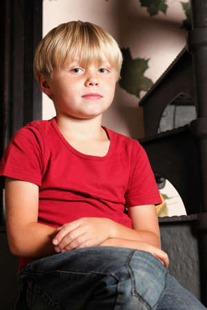 boy in red sitting on stairs, playing indoorの写真素材