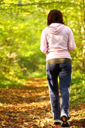 Woman walking cross country and trail in autumn forestの写真素材