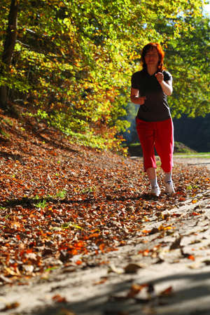 Woman walking cross country and trail in autumn forestの写真素材