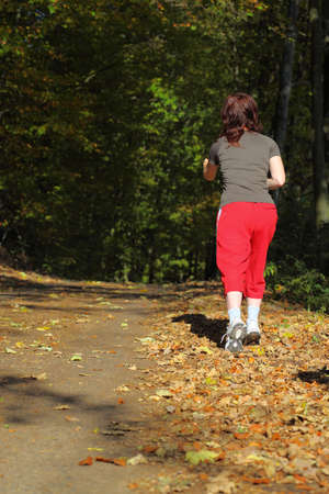 Woman walking cross country and trail in autumn forestの写真素材
