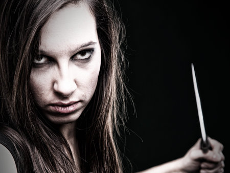 Sexy young woman in red with a knife on green backgroundの写真素材