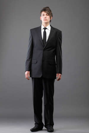 Fashion young businessman black suit casual tie on gray backgroundの写真素材