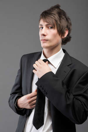 Fashion young businessman black suit casual tie on gray backgroundの写真素材