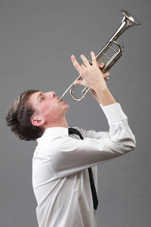 Portrait of a young jazz man playing his Trumpet grey backgroundの写真素材