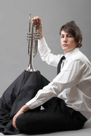 Portrait of a young jazz man and his Trumpet grey backgroundの写真素材