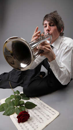 Portrait of a young jazz man playing his Trumpet grey background. Love melodyの写真素材