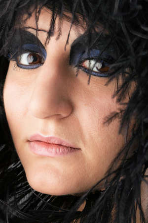 Beautiful Portrait of woman. Studio shot. Professional make up and hair style black featherの写真素材